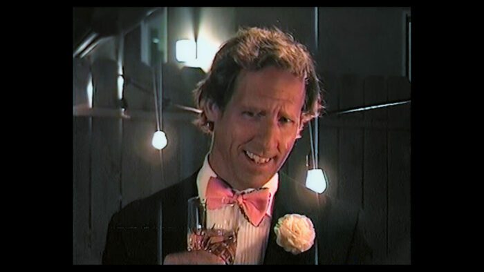 A man in a tuxedo appears on a home video in The Moon & Back.