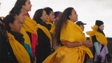 A group of women in yellow attire face the camera