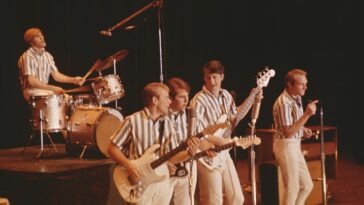 CALIFORNIA - CIRCA 1964: Rock and roll band "The Beach Boys" perform onstage in circa 1964 in California. (L-R) Dennis Wilson, Al Jardine, Carl Wilson, Brian Wilson, Mike Love. (Photo by Michael Ochs Archives/Getty Images). Photo of the Beach Boys performing on stage in their matching striped shirts.