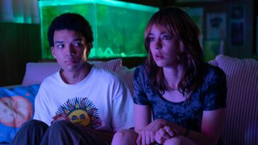 Owen (Justice Smith) and Maddy (Brigitte Lundy-Paine) watch The Pink Opaque with neon pink glowing on them.