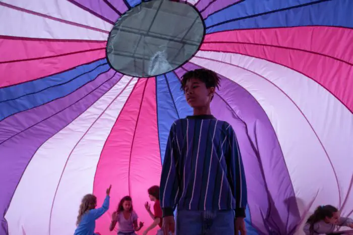Owen as a 7th grader, looking confused under a big pink and blue parachute.
