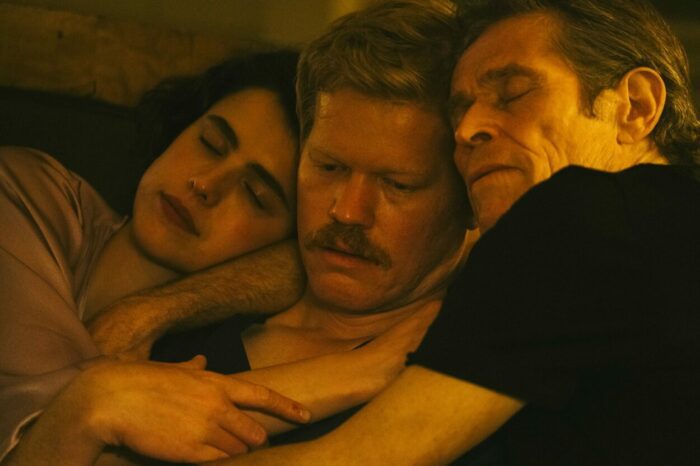 A woman and two men embrace in bed in Kinds of Kindness