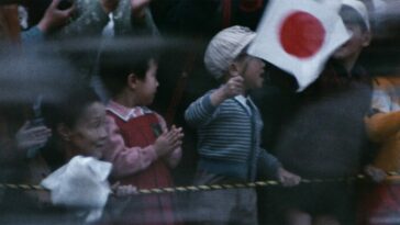 A young boy waves a Japanese flag in Tokyo Olympiad.