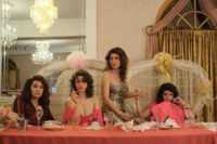 [L-R] Annabella Sciorra, Odessa A’zion, Jennifer Esposito, Emily Bader as Christine, Connie, Francine, and Rose in Fresh Kills (2023). Courtesy of Quiver Distribution. The Larusso ladies and Aunt Christine sitting at the wedding table wearing red bride's maid dresses.