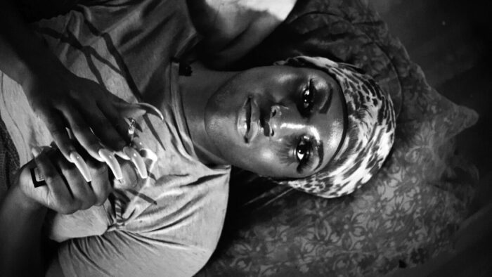A black transgender woman looking up at the camera while lying down in black and white from Kokomo City.