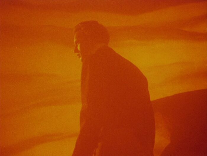 A man stands amid an orange sky in a still from Careful by Guy Maddin