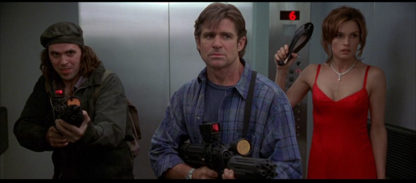Two men stand ready with machine guns while a woman threatens with a shoe in Deep Rising