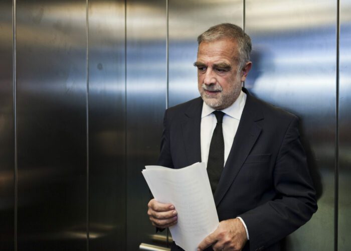 Luis Moreno- Ocampo rides an elevator and holds a sheath of papers in War and Justice.