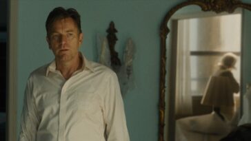 David (Ewan McGregor) stares blankly while Mother is reflected in a mirror as she sits on the display couch.