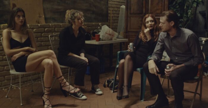 (l-R) Three women and a man set around a table with drinks on an outdoor patio.