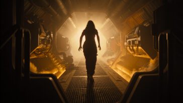 Isabela Merced as Kay in 20th Century Studios' ALIEN: ROMULUS. Photo courtesy of 20th Century Studios. © 2024 20th Century Studios. All Rights Reserved. Kay walking the claustrophobic halls of a derelict space station.