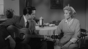 Johnny (Johnny Cash) plays a song on guitar as Nancy (Cay Forester) watches in Door-to-Door Maniac