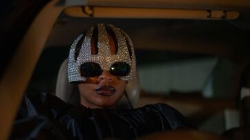 Shula wearing a bedazzled helmet sits in her car from a TIFF24 film.